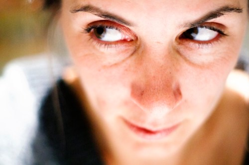 Close-up of a woman's face, focusing on her eyes and expression, with soft lighting and a blurred background.