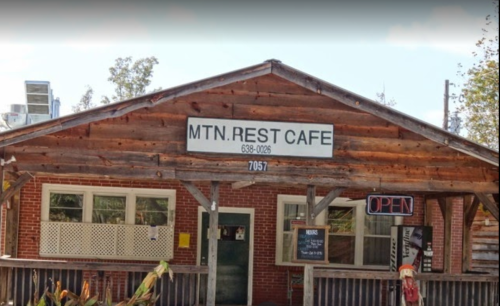 A rustic wooden cafe with a sign reading "MTN. REST CAFE" and an "OPEN" sign on the porch.