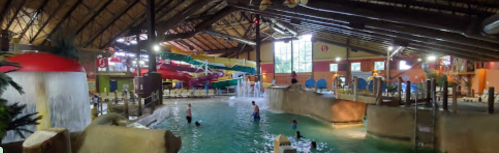 Indoor water park featuring slides, a pool, and children playing in a tropical-themed environment.
