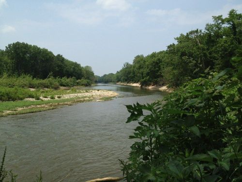 A serene river winding through lush greenery under a clear blue sky.
