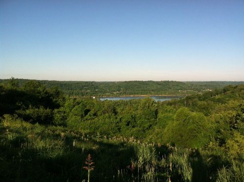 A scenic view of a lush green landscape with a river winding through the valley under a clear blue sky.