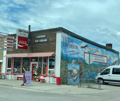 A vintage ice cream shop with a colorful mural, striped awning, and a sign for a soda fountain.