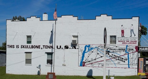 Mural on a building in Skullbone, Tennessee, featuring maps and text about the town's name and history.