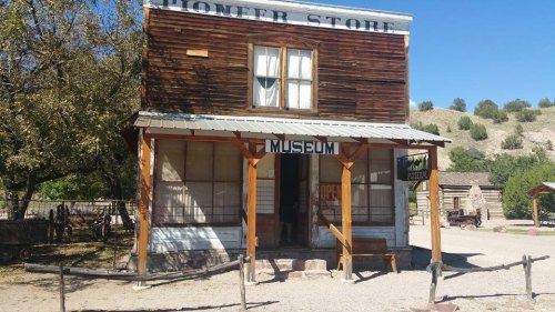 A rustic pioneer store building with a sign reading "Museum," surrounded by trees and a dirt path.