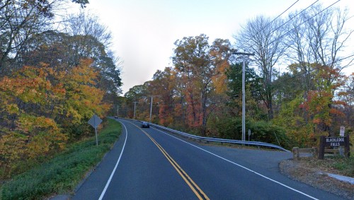 A winding road surrounded by colorful autumn trees, leading to a sign for Blackledge Falls.