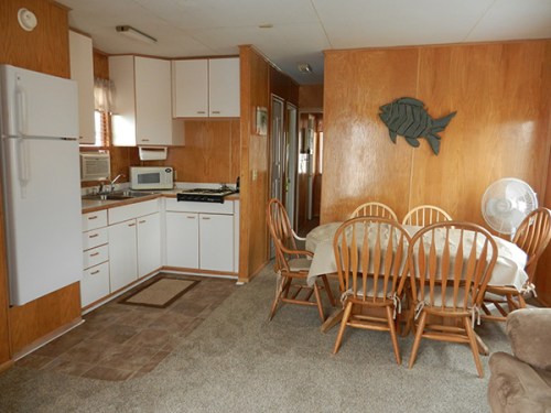 A cozy kitchen and dining area with wooden cabinets, a table with chairs, and a fish decoration on the wall.