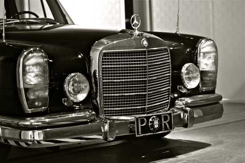 Classic black Mercedes-Benz with a distinctive grille and vintage license plate, showcased in a museum setting.