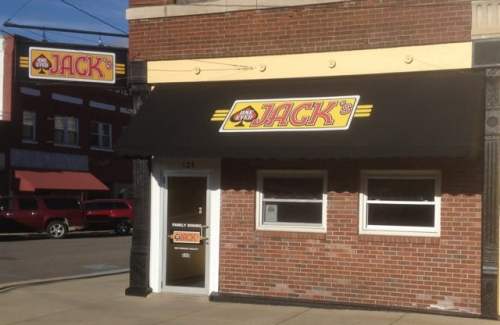 A brick building with a black awning and a sign reading "Jack's" in yellow and red. Windows are visible on the front.