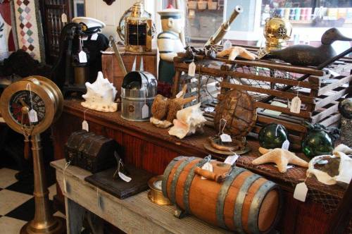 A display of various vintage items, including nautical decor, shells, and antique containers on a wooden table.