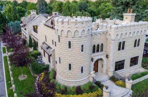 Aerial view of a stone castle-like house surrounded by greenery and colorful flowers.