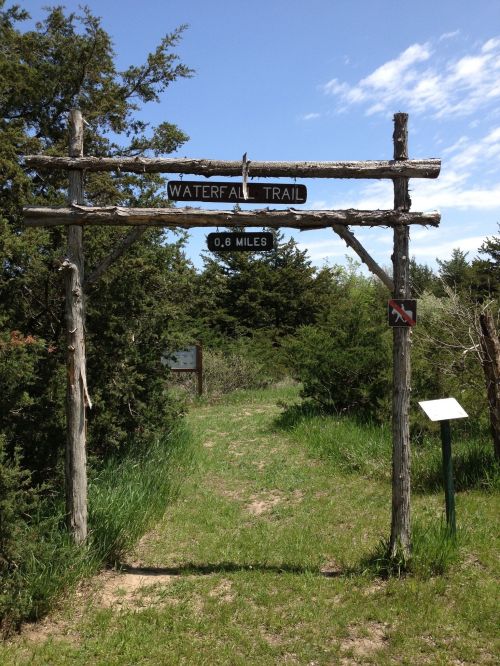 Sign for Waterfall Trail, indicating a distance of 0.6 miles, surrounded by greenery and trees.