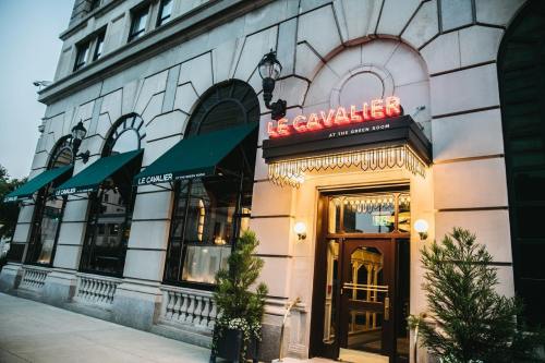 Exterior of Le Cavalier restaurant, featuring a stylish entrance and green awnings, set in an elegant building.