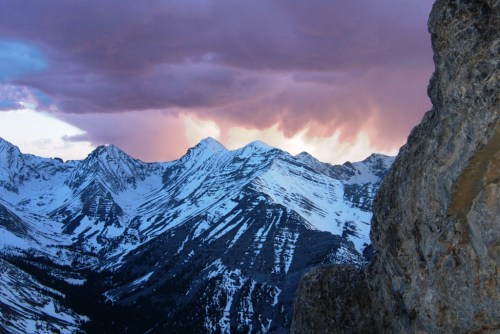 Snow-capped mountains under a dramatic pink and purple sky at sunset.