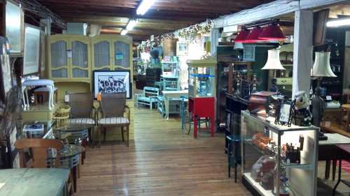 A cozy antique shop interior filled with various vintage furniture and decor items, illuminated by warm lighting.
