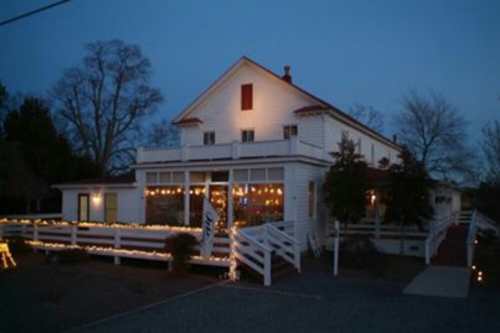 A charming white house with festive lights, set against a twilight sky, showcasing a welcoming atmosphere.
