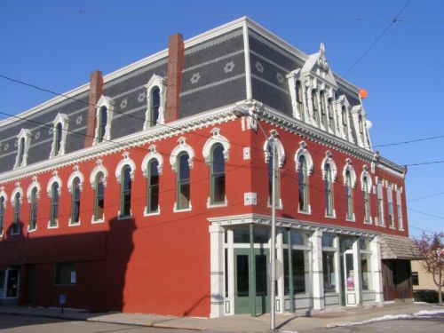 Historic red brick building with ornate white trim and large windows, set against a clear blue sky.