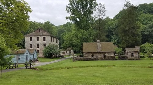 Historic buildings surrounded by lush greenery, with a pathway leading through a serene landscape.