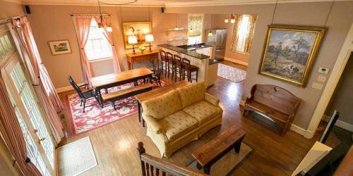 A cozy living space featuring a sofa, dining table, and kitchen with bar stools, all in warm, inviting tones.