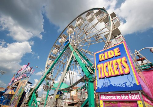 A colorful fair scene featuring a large Ferris wheel and a "Ride Tickets" sign under a cloudy sky.