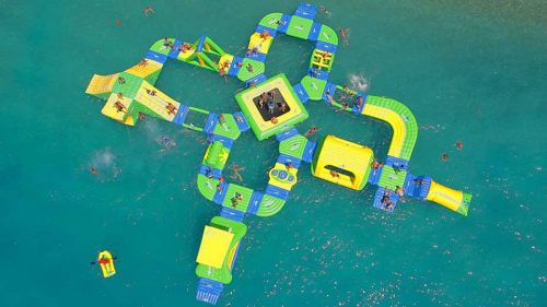 Aerial view of a colorful water park with inflatable structures and people enjoying the water.