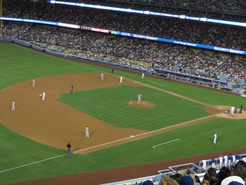 A baseball game in progress at a stadium, with players on the field and a large crowd in the stands.