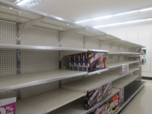 Empty store shelves with a few toy boxes visible, indicating low stock or clearance sale.