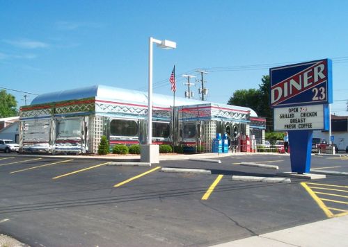 A shiny, retro diner with a silver exterior and colorful accents, featuring a sign that reads "DINER 23."