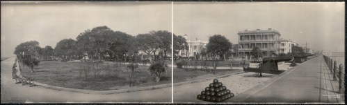 A panoramic view of a park with trees, a building, and a cannon on display along a walkway.