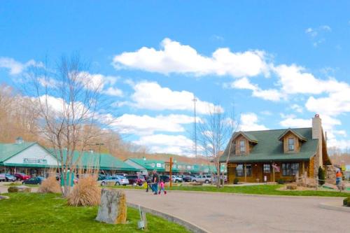 A charming building with a green roof, surrounded by trees and a parking lot, under a blue sky with fluffy clouds.