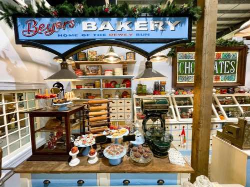 A charming bakery display featuring baked goods, a vintage scale, and festive decorations under a sign that reads "Beyers Bakery."