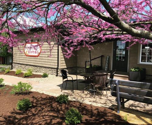 A charming bistro with a welcoming sign, surrounded by blooming pink flowers and a landscaped garden.