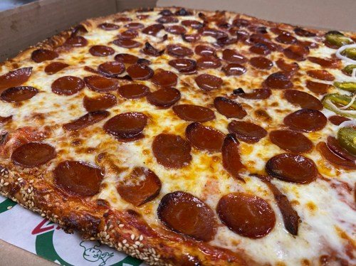 A close-up of a pepperoni pizza with a golden crust, melted cheese, and slices of pepperoni in a pizza box.