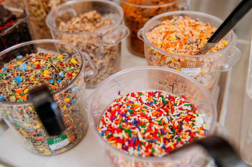 Colorful sprinkles and toppings in clear containers, ready for decorating desserts.