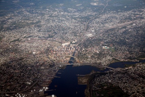 Aerial view of a city with a river, bridges, and urban development surrounded by greenery.