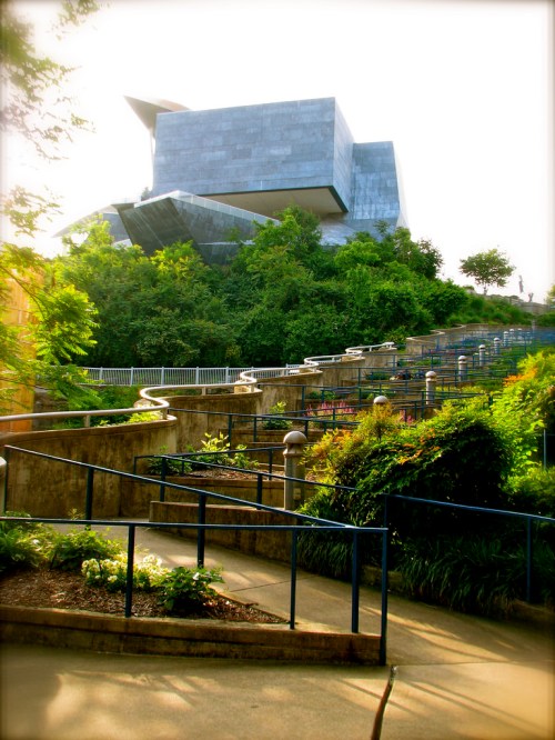 A modern building surrounded by lush greenery and pathways, showcasing a blend of architecture and nature.
