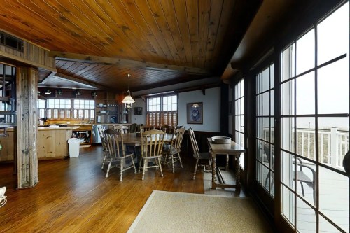 Cozy interior of a wooden cabin with a dining area, large windows, and rustic decor.