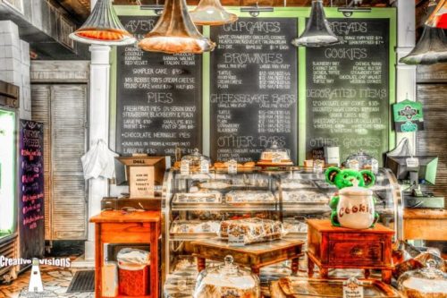 A bakery display with various desserts, including cupcakes, cookies, and pies, against a chalkboard menu backdrop.