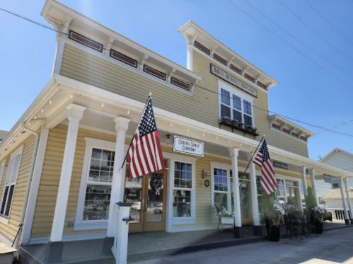 A charming yellow building with American flags, featuring large windows and a sign for "Cedar Point Community."