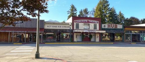 A small town street featuring the Concrete Theatre, Act One Ice Cream, and a building labeled "HUB" with trees in the background.