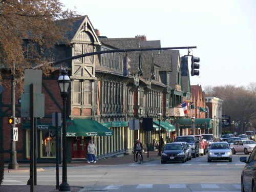 A charming street lined with historic buildings, shops, and traffic lights, with pedestrians and cyclists visible.