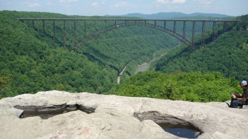 A scenic view of a lush green valley with a large bridge spanning across it, under a clear blue sky.