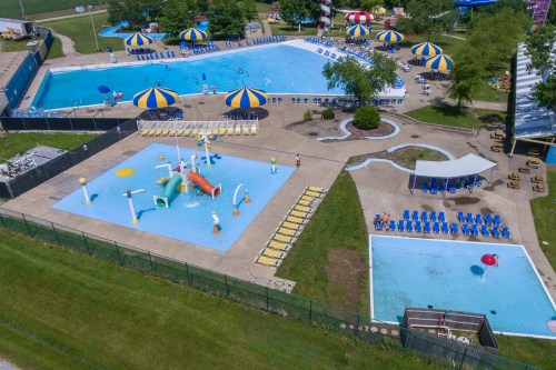 Aerial view of a water park featuring multiple pools, colorful umbrellas, and water play structures.