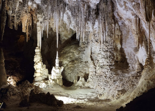 Stalactites and stalagmites in a dimly lit cave, showcasing unique rock formations and textures.