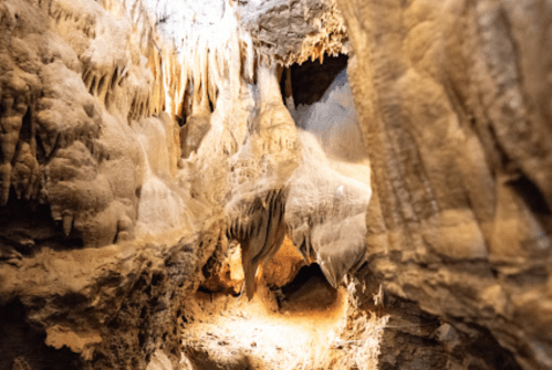 Stalactites and stalagmites in a dimly lit cave, showcasing intricate rock formations and textures.