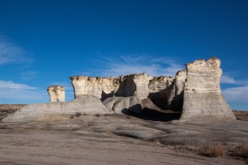 A rugged rock formation under a clear blue sky, showcasing unique geological structures and textures.