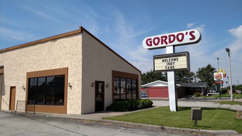 A restaurant named Gordo's with a sign welcoming Indy fans, set against a clear blue sky.