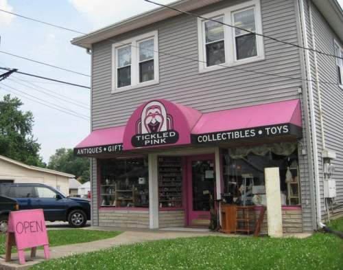 A pink storefront labeled "Tickled Pink" selling antiques, gifts, collectibles, and toys, with an "Open" sign.