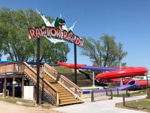 Colorful water slide attraction named "Raptor Rapids" with a wooden deck and clear blue sky in the background.