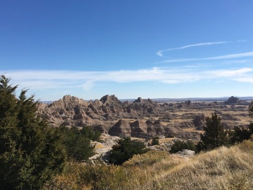 A panoramic view of rugged rock formations and grassy plains under a clear blue sky.