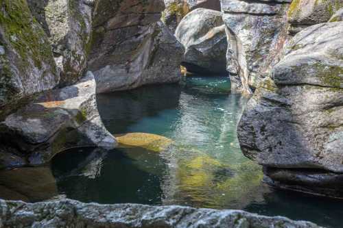 A serene natural scene featuring smooth rocks surrounding a clear, tranquil pool of water.